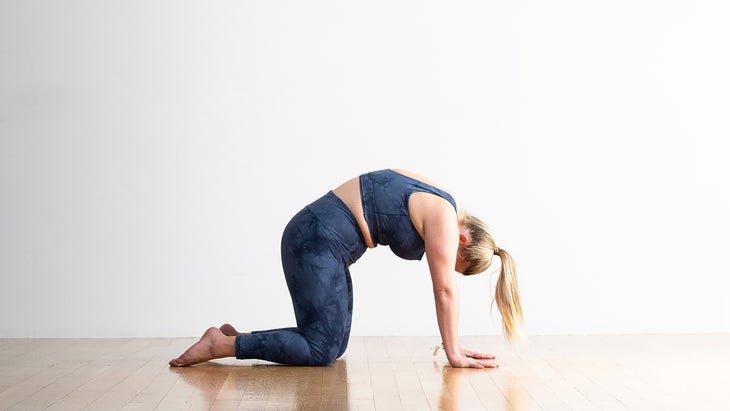 A person demonstrates Cat Pose (Marjaryasana) in yoga