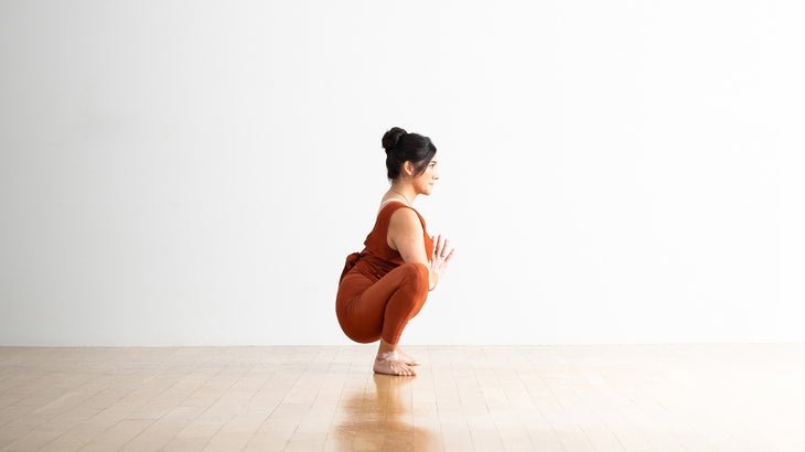 Una persona demuestra una postura en cuclillas o guirnalda en yoga